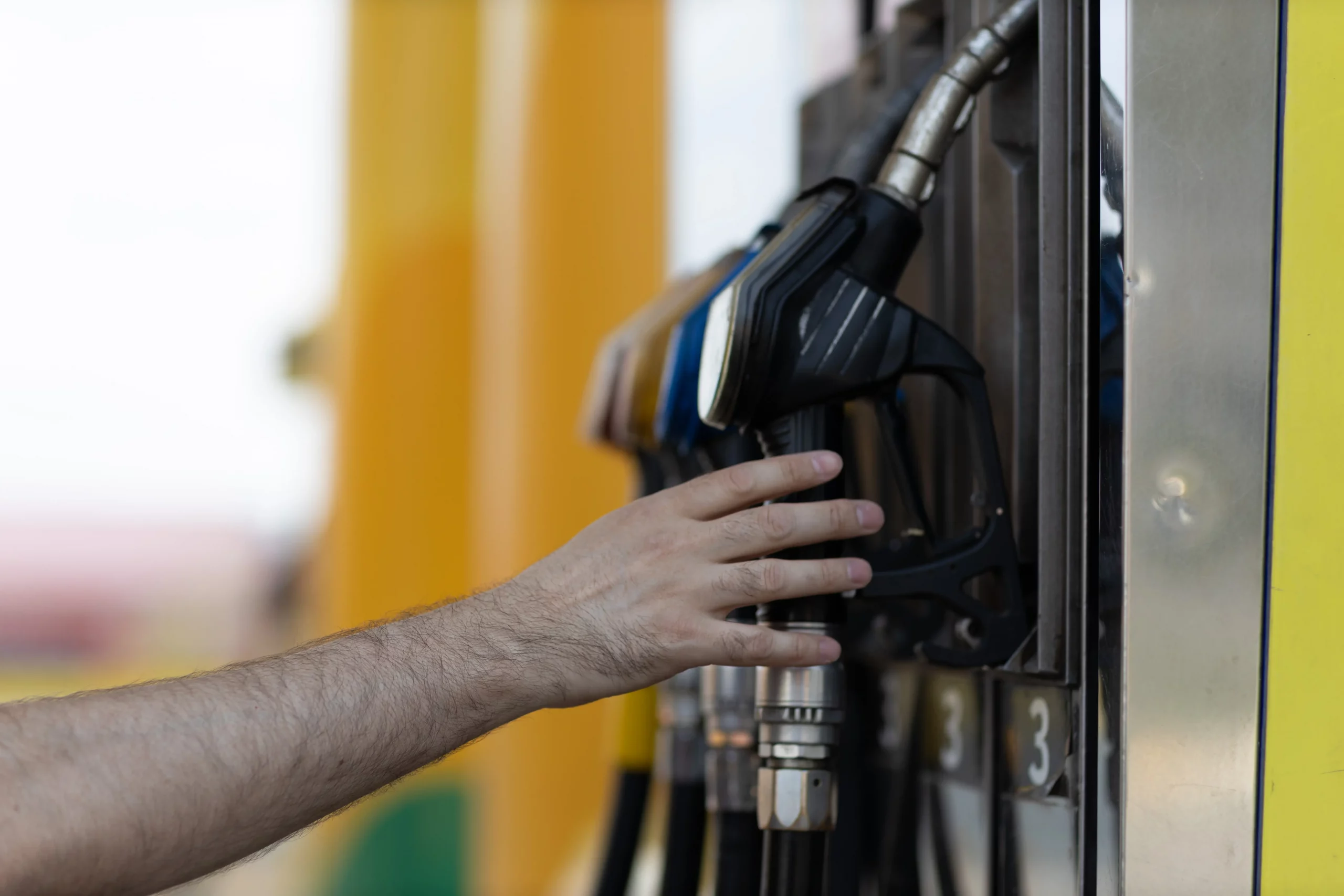 Close-up of a person's hand holding a black fuel pump at a gas station, symbolizing the use of flex fuel options in modern transportation.