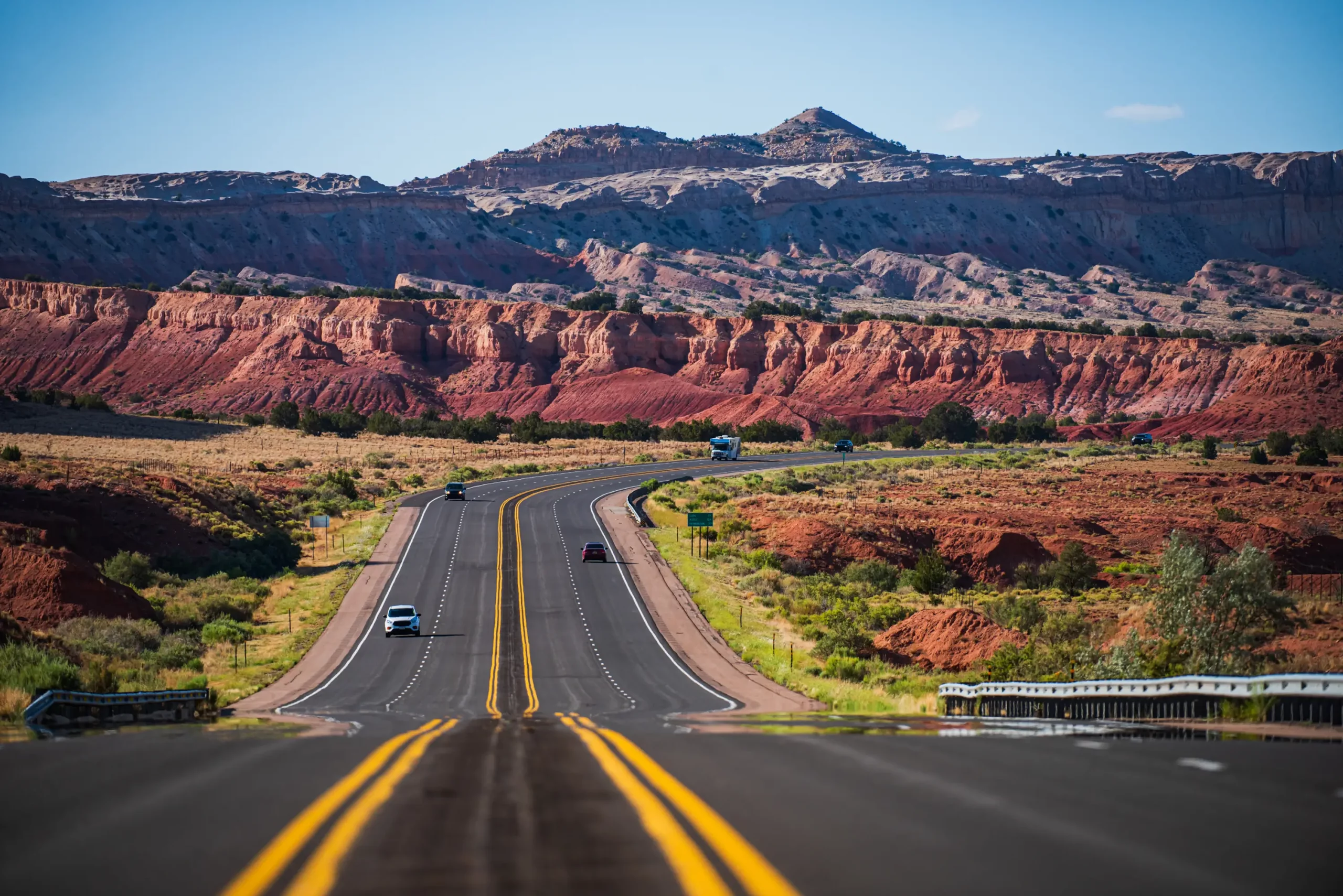 A winding highway in a picturesque landscape with vibrant red rock formations under a clear blue sky, symbolizing high-quality road infrastructure.